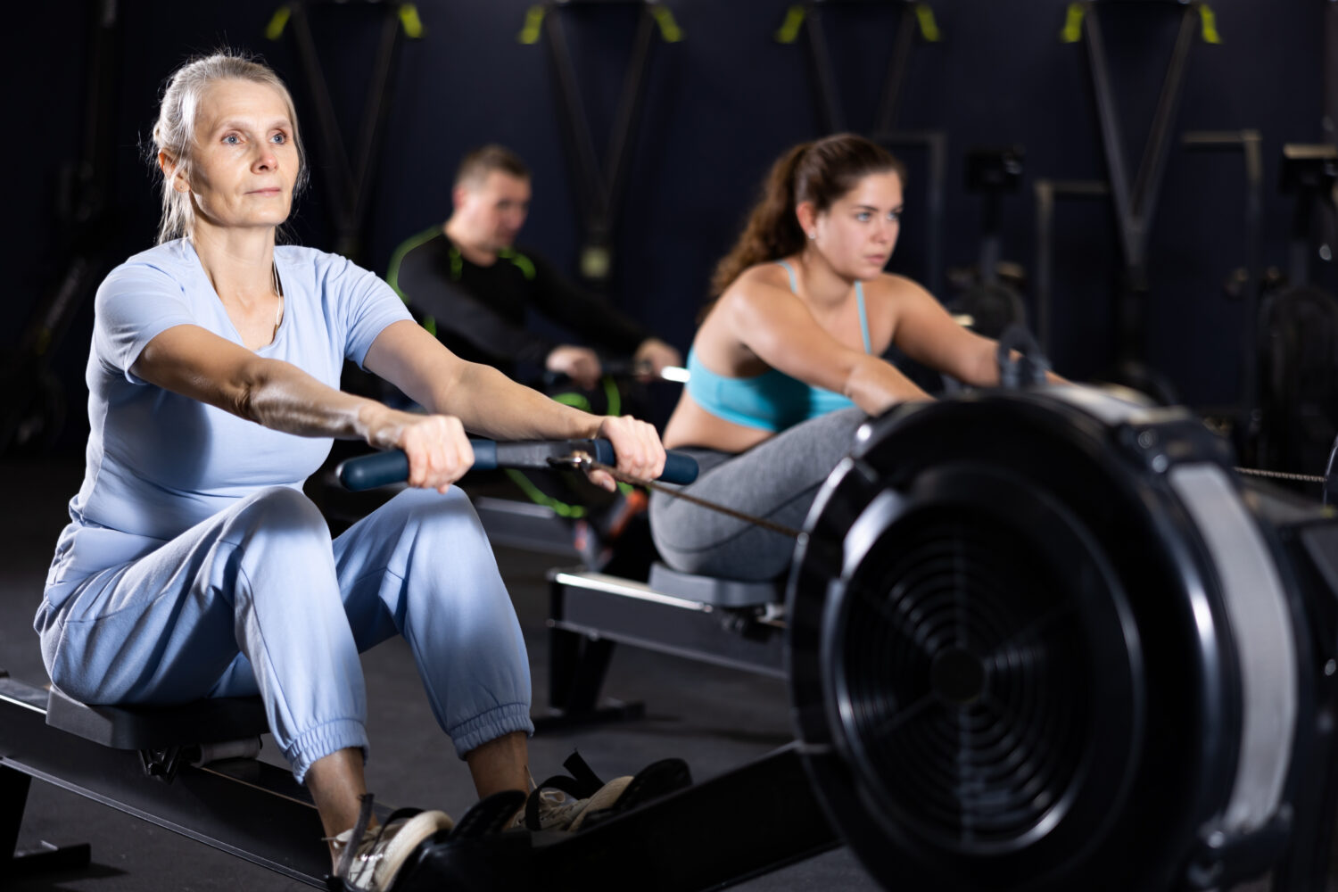 Senior woman working out on rowing machine in gym